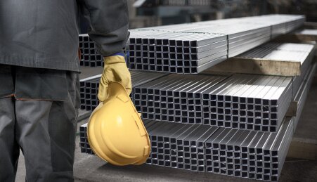 worker with helmet in front of steel metal profiles